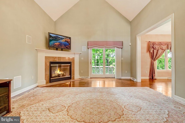 unfurnished living room featuring hardwood / wood-style flooring, a healthy amount of sunlight, and high vaulted ceiling