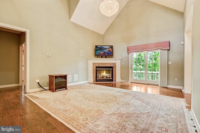 unfurnished living room with wood-type flooring, a chandelier, and high vaulted ceiling