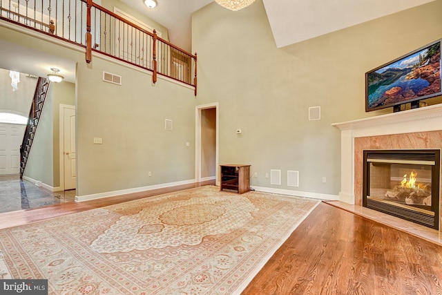 unfurnished living room with a high ceiling, a fireplace, and hardwood / wood-style floors