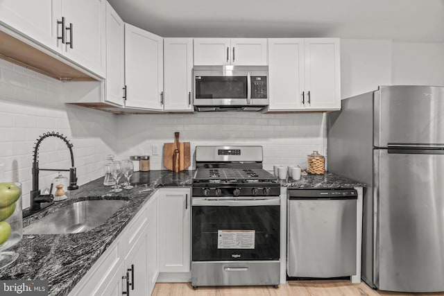 kitchen with light wood-type flooring, white cabinets, appliances with stainless steel finishes, and sink