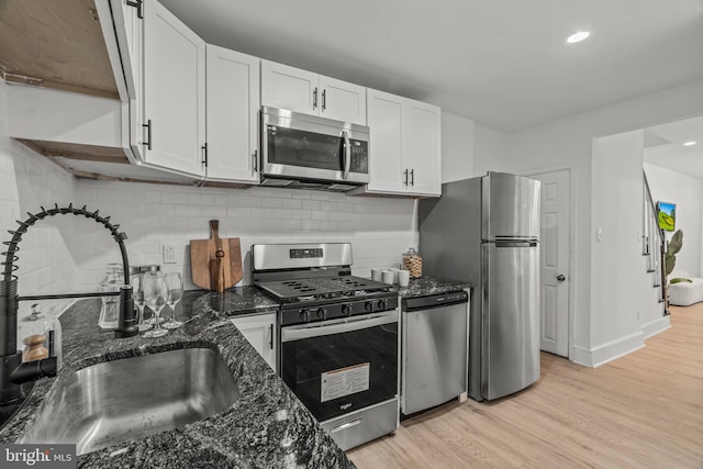 kitchen with white cabinets, sink, tasteful backsplash, light hardwood / wood-style flooring, and appliances with stainless steel finishes