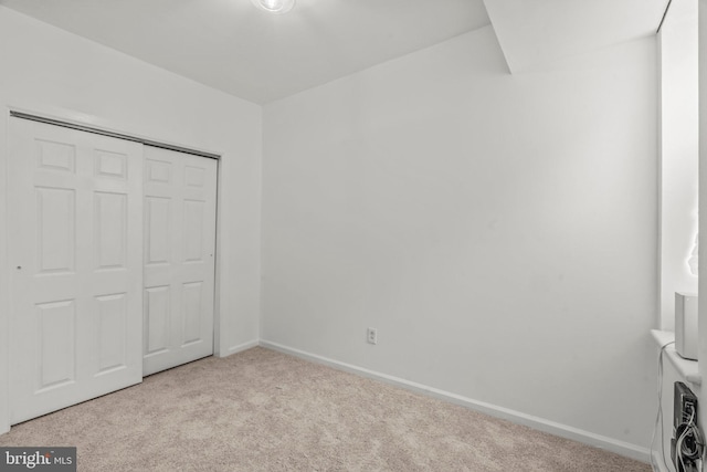 unfurnished bedroom featuring light carpet and a closet