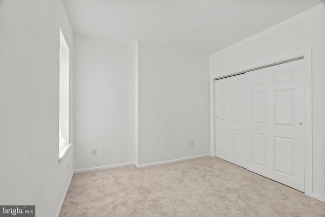 unfurnished bedroom featuring light carpet and a closet