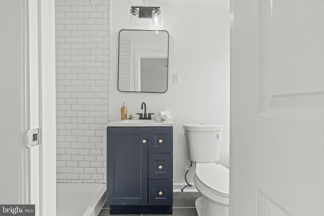 bathroom with tiled shower, vanity, and toilet