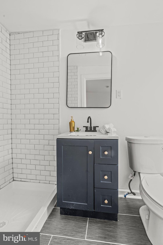 bathroom featuring tiled shower, vanity, and toilet