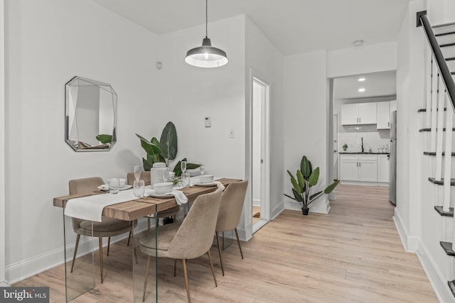 dining space with light wood-type flooring and sink