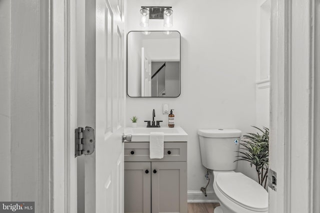 bathroom featuring wood-type flooring, vanity, and toilet