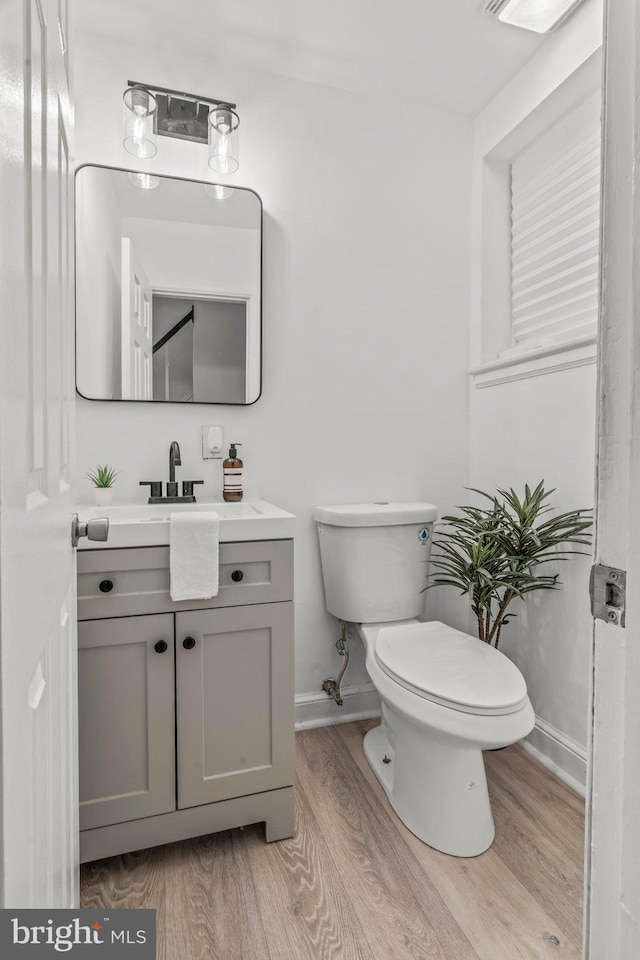 bathroom with hardwood / wood-style floors, vanity, and toilet