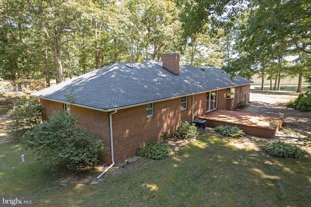 rear view of house with central AC unit and a yard