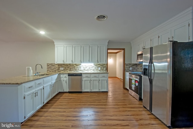 kitchen featuring stainless steel appliances, white cabinets, and light wood-type flooring