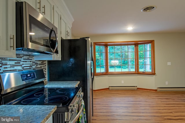 kitchen with a baseboard radiator, appliances with stainless steel finishes, light wood-type flooring, and white cabinetry