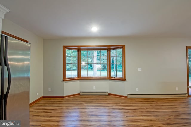 unfurnished room with a baseboard radiator and light hardwood / wood-style floors