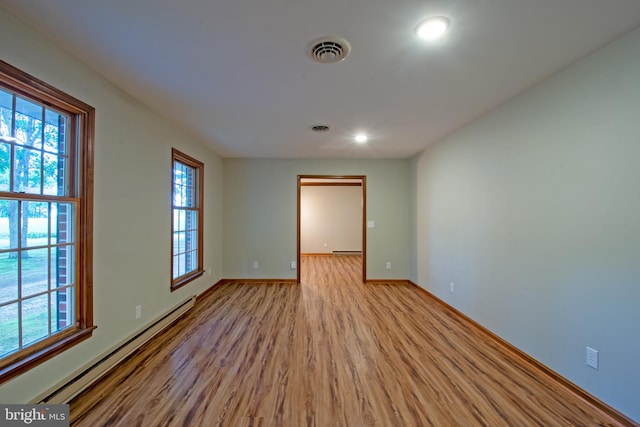 unfurnished room with light wood-type flooring and a baseboard heating unit