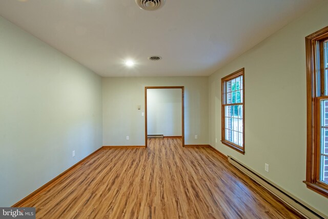 empty room with light wood-type flooring and baseboard heating