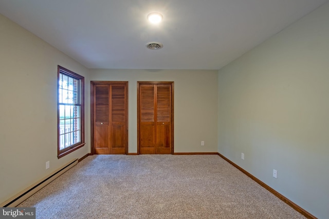 unfurnished bedroom featuring carpet floors, multiple closets, and a baseboard radiator