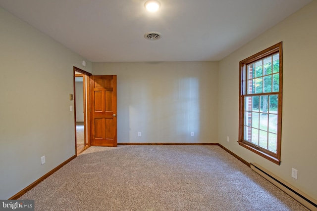 spare room with light carpet and a baseboard heating unit