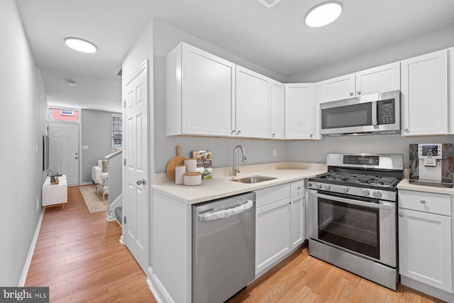 kitchen with white cabinets, light hardwood / wood-style flooring, stainless steel appliances, and sink