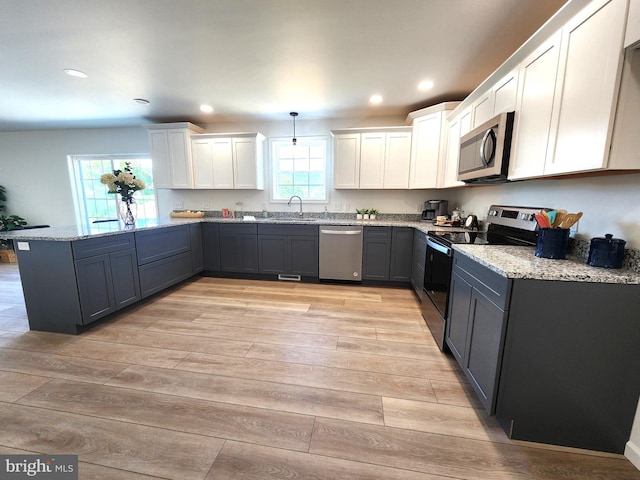 kitchen with white cabinets, pendant lighting, light hardwood / wood-style flooring, appliances with stainless steel finishes, and light stone countertops