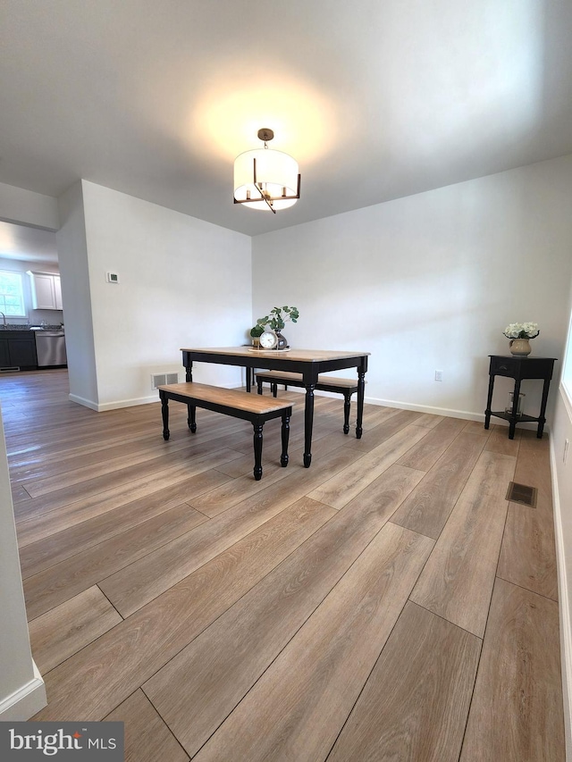 dining space featuring light wood-type flooring and an inviting chandelier