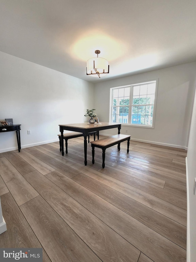 unfurnished dining area with wood-type flooring and a notable chandelier