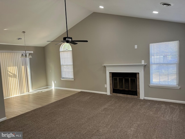 unfurnished living room featuring ceiling fan with notable chandelier, high vaulted ceiling, and hardwood / wood-style flooring