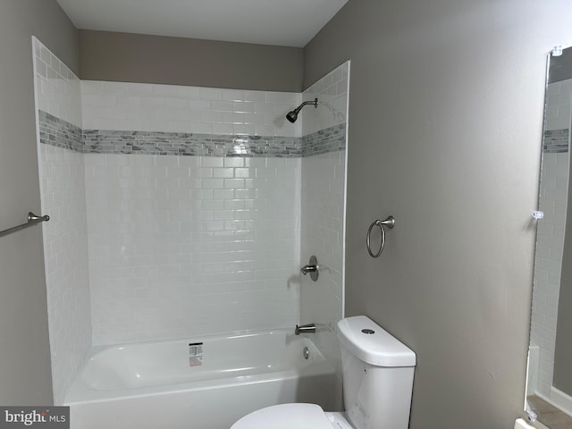 bathroom with tiled shower / bath combo and toilet