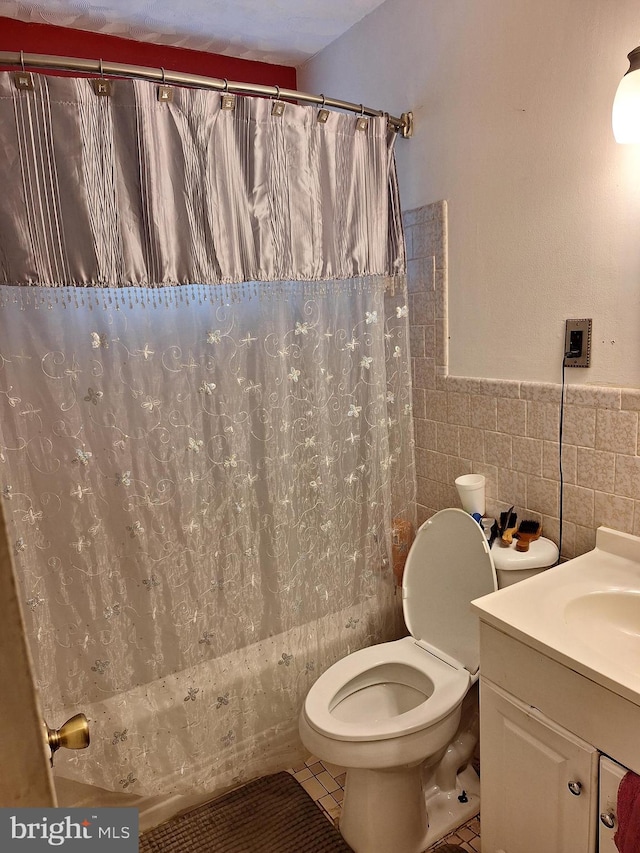 full bathroom featuring shower / bath combination with curtain, tile walls, tile patterned floors, vanity, and toilet