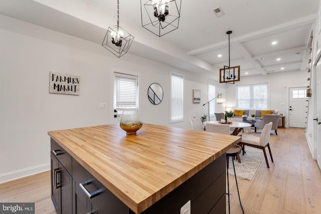 kitchen with coffered ceiling, a notable chandelier, light hardwood / wood-style flooring, a center island, and beam ceiling