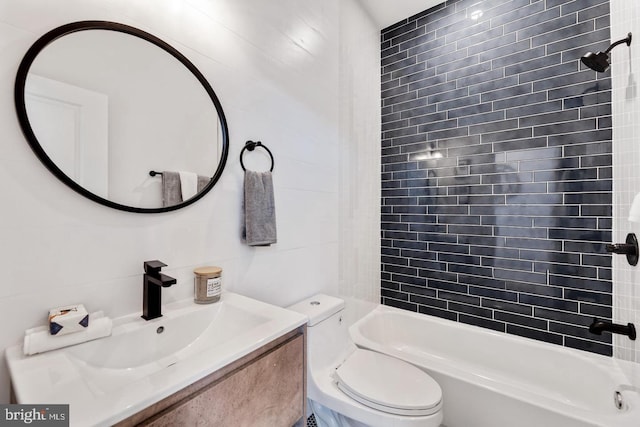 full bathroom featuring tiled shower / bath combo, vanity, toilet, and tile walls