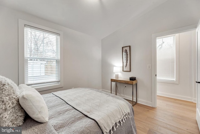 bedroom with multiple windows, lofted ceiling, and light hardwood / wood-style flooring