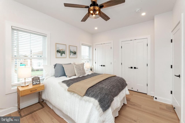 bedroom with two closets, ceiling fan, and light wood-type flooring