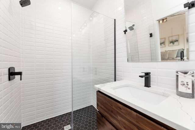 bathroom with tile walls, a tile shower, tasteful backsplash, and vanity