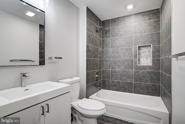 full bathroom featuring tile patterned flooring, tiled shower / bath, vanity, and toilet