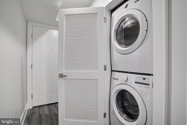 laundry room with dark wood-type flooring and stacked washer and dryer