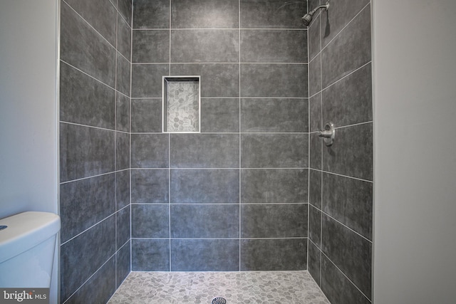 bathroom featuring tiled shower and toilet