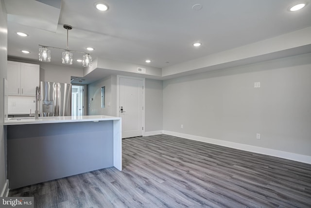 kitchen featuring pendant lighting, white cabinets, kitchen peninsula, stainless steel fridge with ice dispenser, and light hardwood / wood-style floors