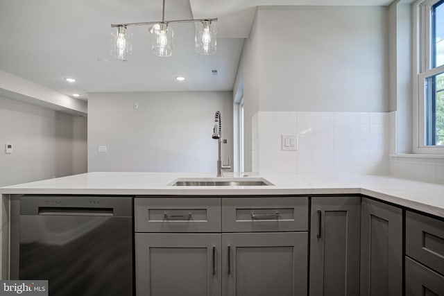 kitchen featuring pendant lighting, sink, gray cabinetry, dishwasher, and light stone countertops