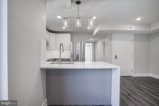 kitchen with white cabinetry, dark wood-type flooring, kitchen peninsula, stainless steel appliances, and decorative light fixtures