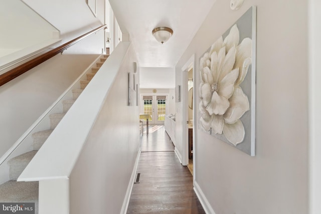corridor featuring stairway, french doors, baseboards, and wood finished floors