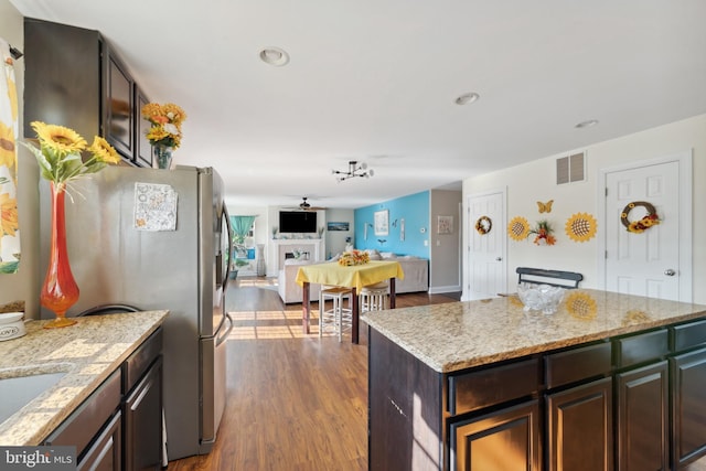 kitchen with visible vents, dark wood finished floors, a fireplace, freestanding refrigerator, and open floor plan