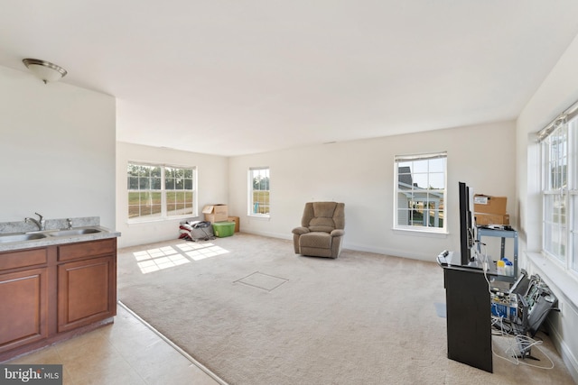 living area featuring plenty of natural light, light colored carpet, and baseboards