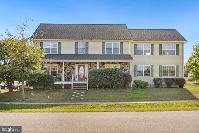 view of front of house with stone siding, covered porch, and a front lawn