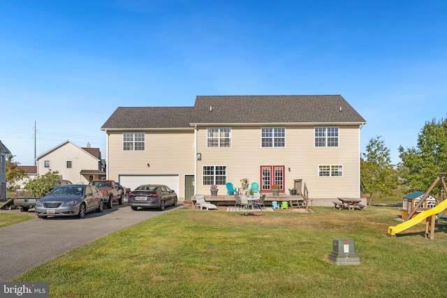 rear view of house with a garage, a playground, and a yard