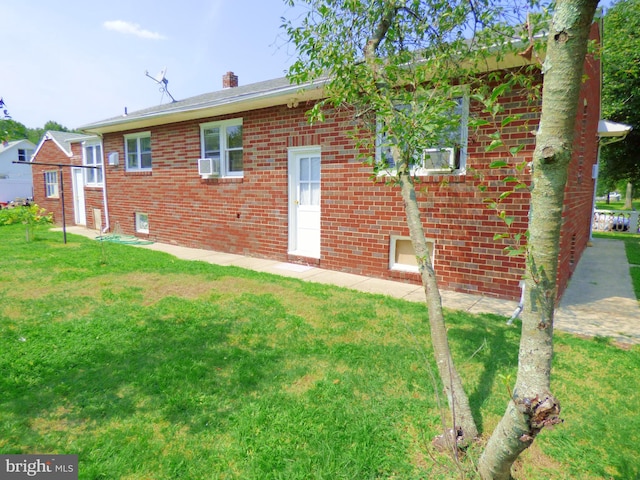 rear view of house featuring cooling unit and a lawn