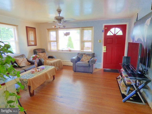 living room with baseboard heating, ceiling fan, and wood-type flooring