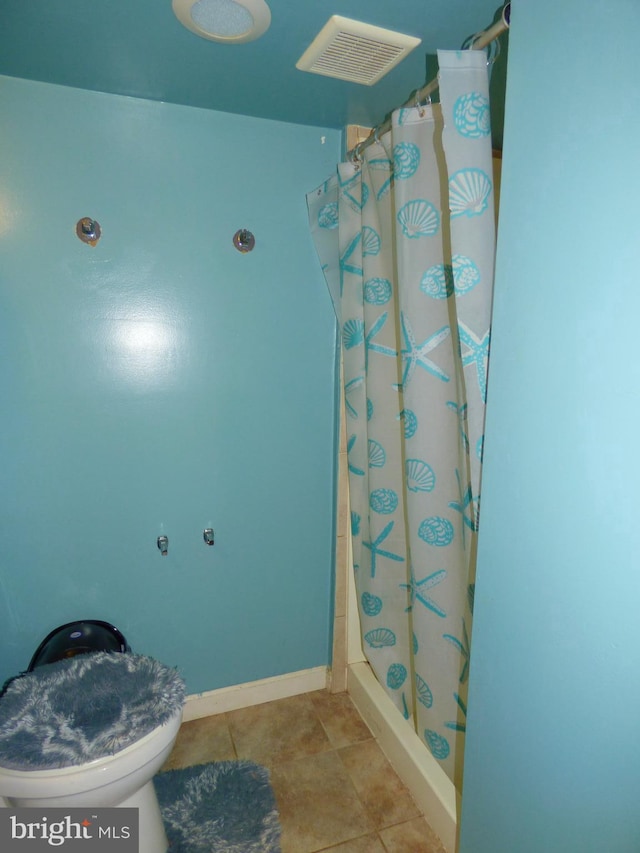 bathroom with toilet, walk in shower, and tile patterned floors