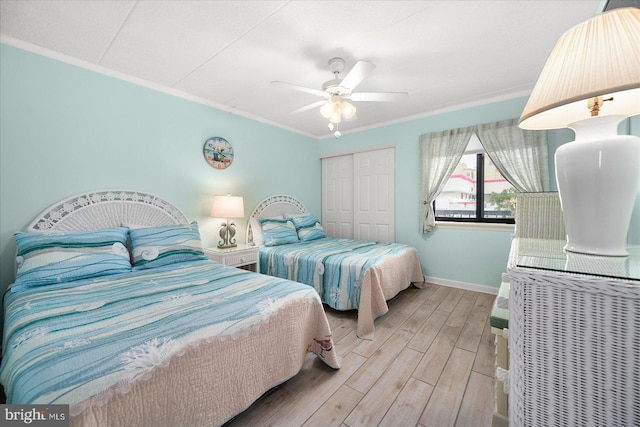 bedroom featuring ceiling fan, light hardwood / wood-style flooring, crown molding, and a closet