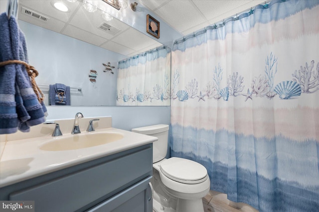 bathroom with a drop ceiling, hardwood / wood-style flooring, vanity, and toilet