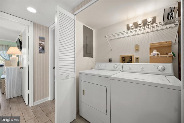 clothes washing area featuring separate washer and dryer, electric panel, and light wood-type flooring