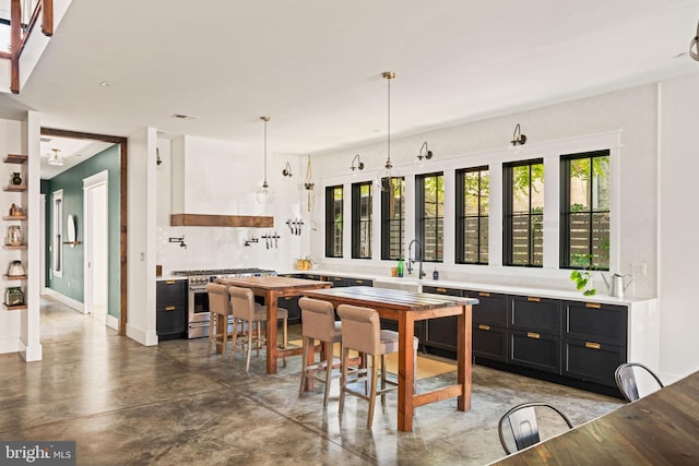 kitchen with pendant lighting, custom exhaust hood, high end stove, and sink